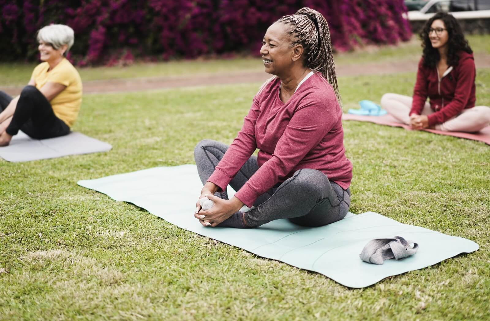 A senior participates in an outdoor yoga class, performing hip stretches to promote mobility and reduce fall risks