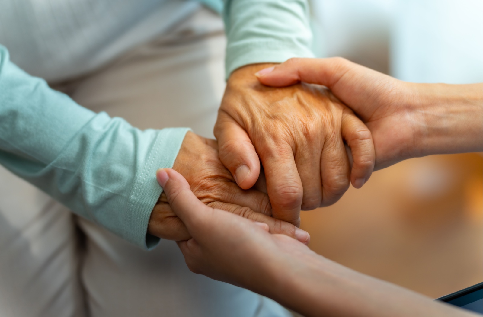 A caregiver holds a senior's hands.