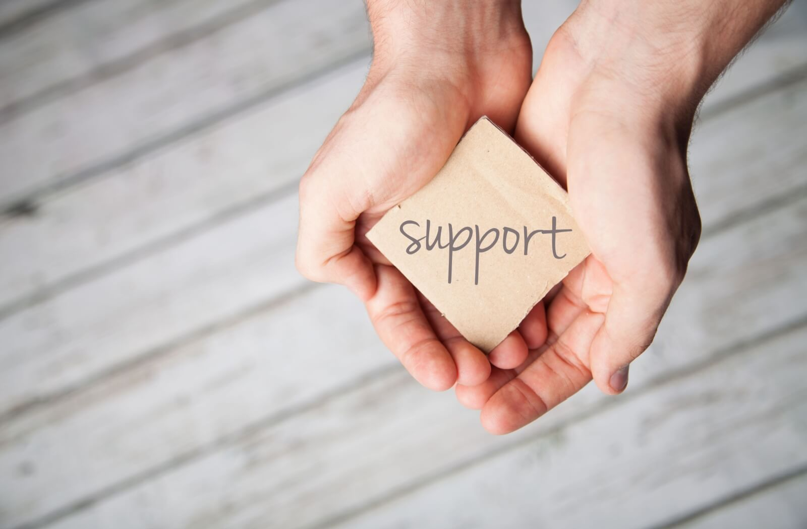 The word "support" is being gently held in hands.
