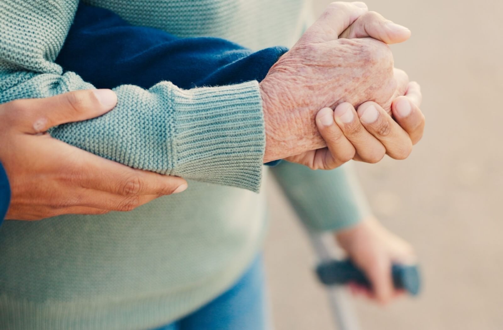 A caregiver helps an older adult tighten their form and grip during a hand-strengthening exercise

