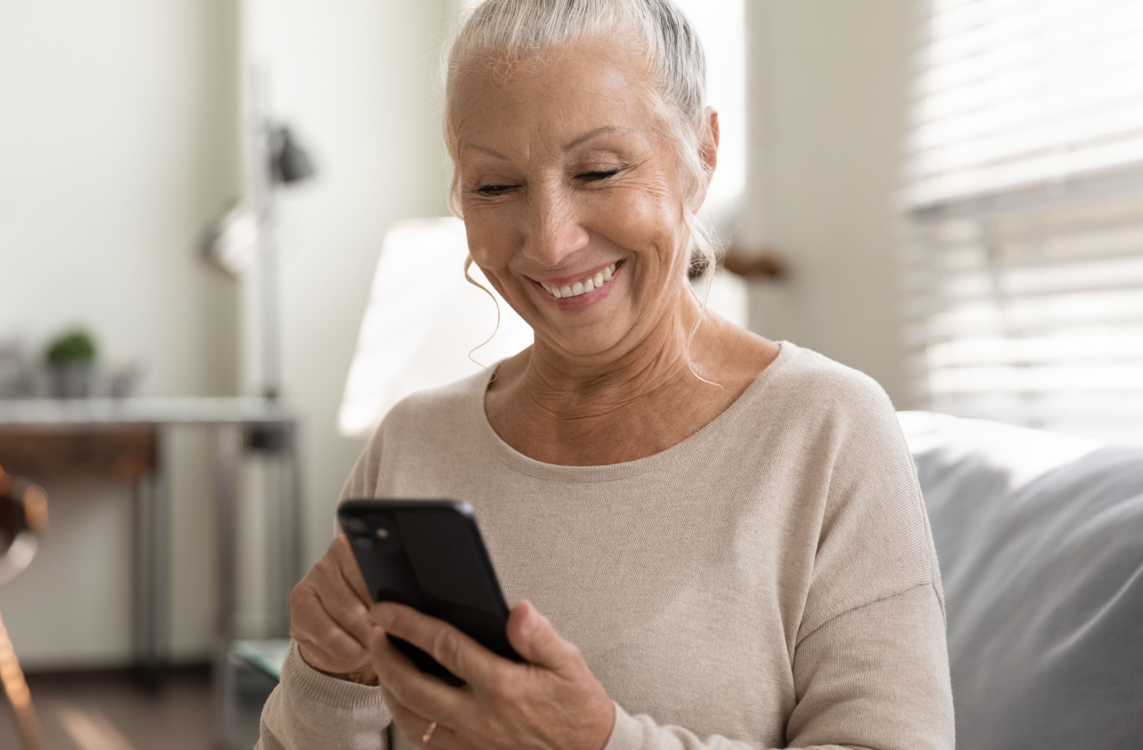 A smiling senior woman uses her cellphone.