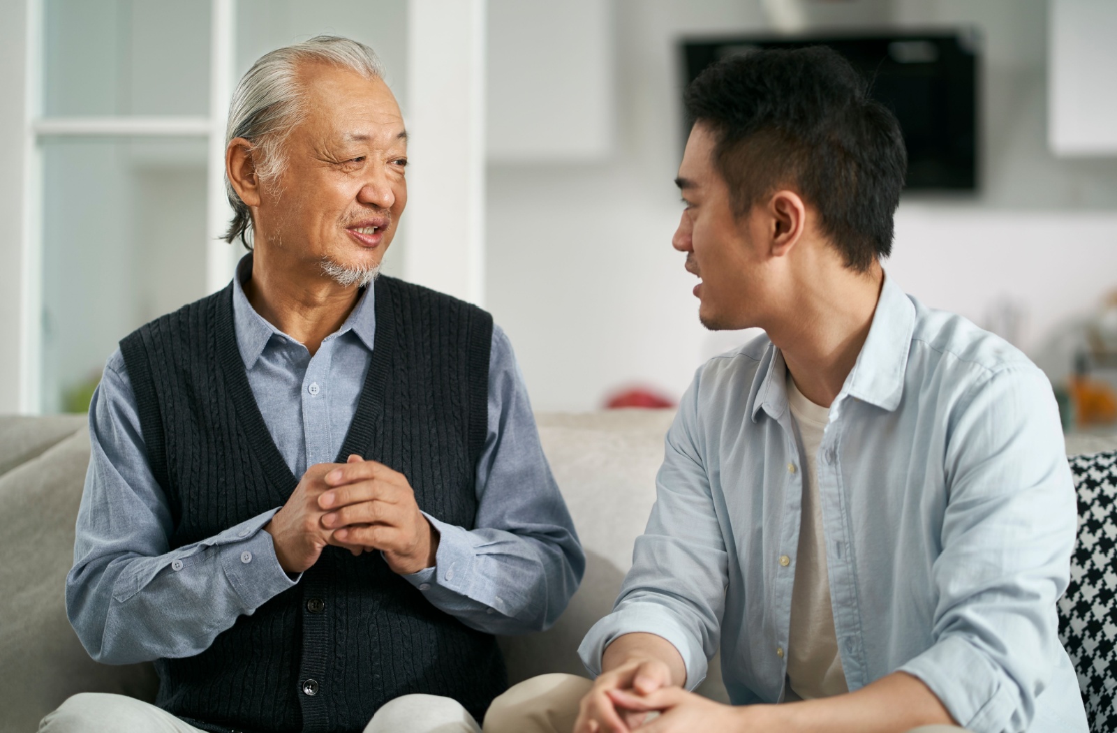 An older father and son enjoying an engaging conversation together.
