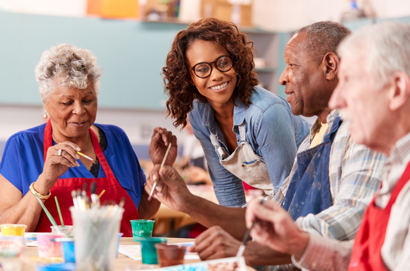 A group of smiling older adults sitting at a table and painting.