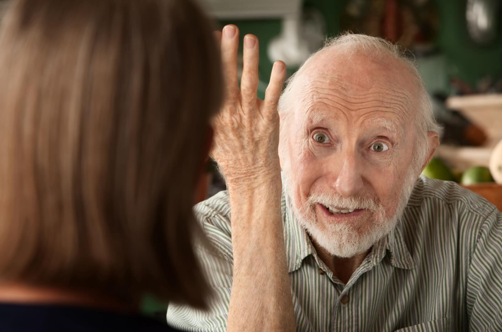 A close up image of a frustrated older adult with dementia during a conversation with a family member.