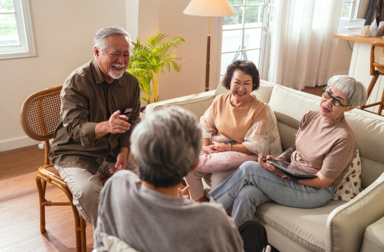 A group of happy senior laughing and chatting with each other in a common area of their assisted living community.