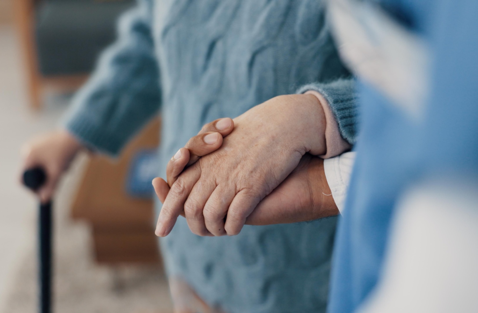 A close-up of an older adult walking and holding hands with a caregiver in memory care.